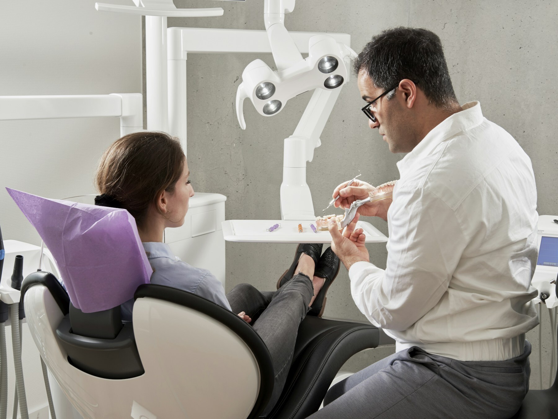 A dentist speaking with a patient in a treatment room